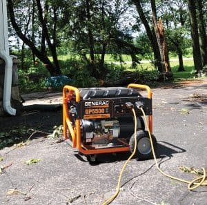 GP5500 Portable Generator on driveway with extension cords with downed trees and limbs.