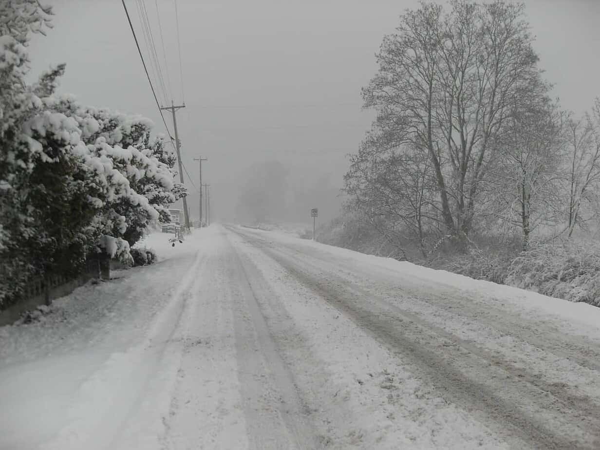A snow covered road during a storm with limited visibility