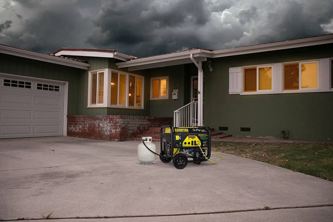 A Portable Generator for Home backup power sits in a driveway. A cord runs from the generator to the house. Inside, the lights are on. thanks to power from the generator