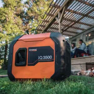 Generac IQ3500 Portable Inverter Generator in a yard with couple sitting on the home's porch.